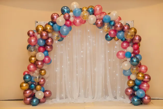 Multicolour balloon arrangement by a white curtain